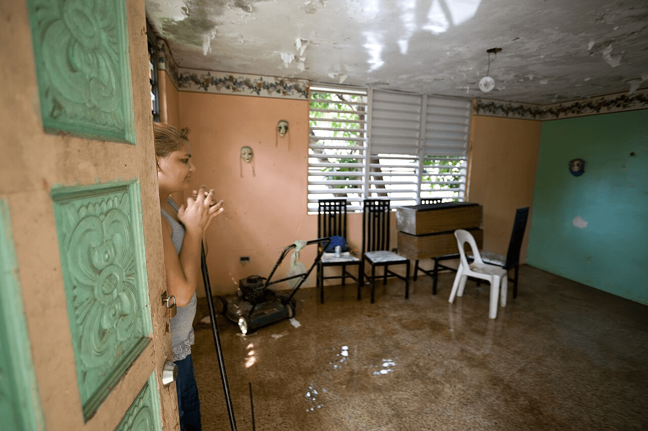 Flooded living room with standing gray water across the floor and water damage on the ceiling