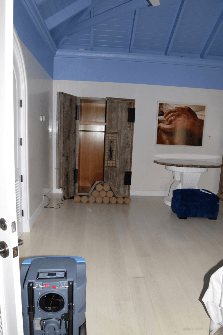 Air mover and LGR dehumidifier staged on a hardwood floor during structural drying
