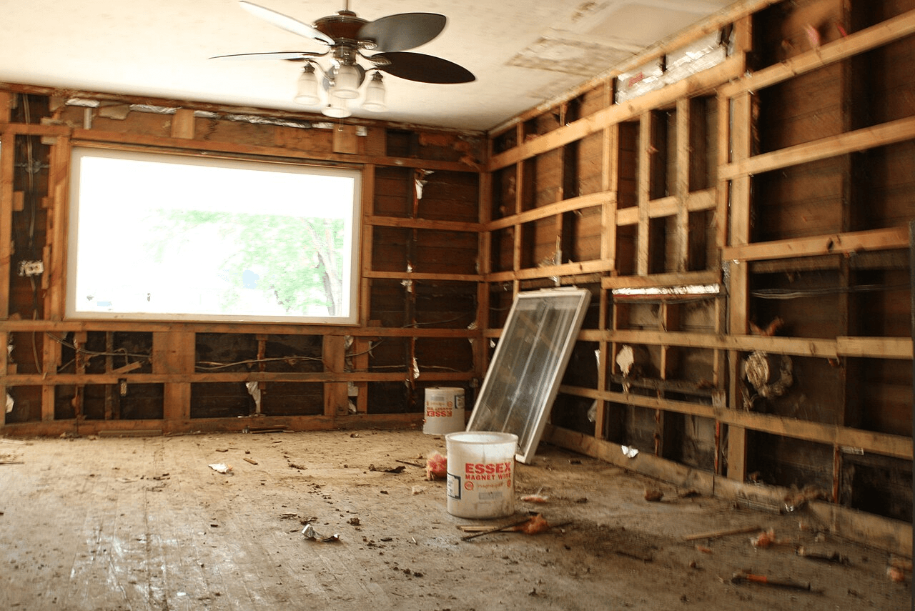 Room with the wall opened to studs exposing saturated drywall and insulation